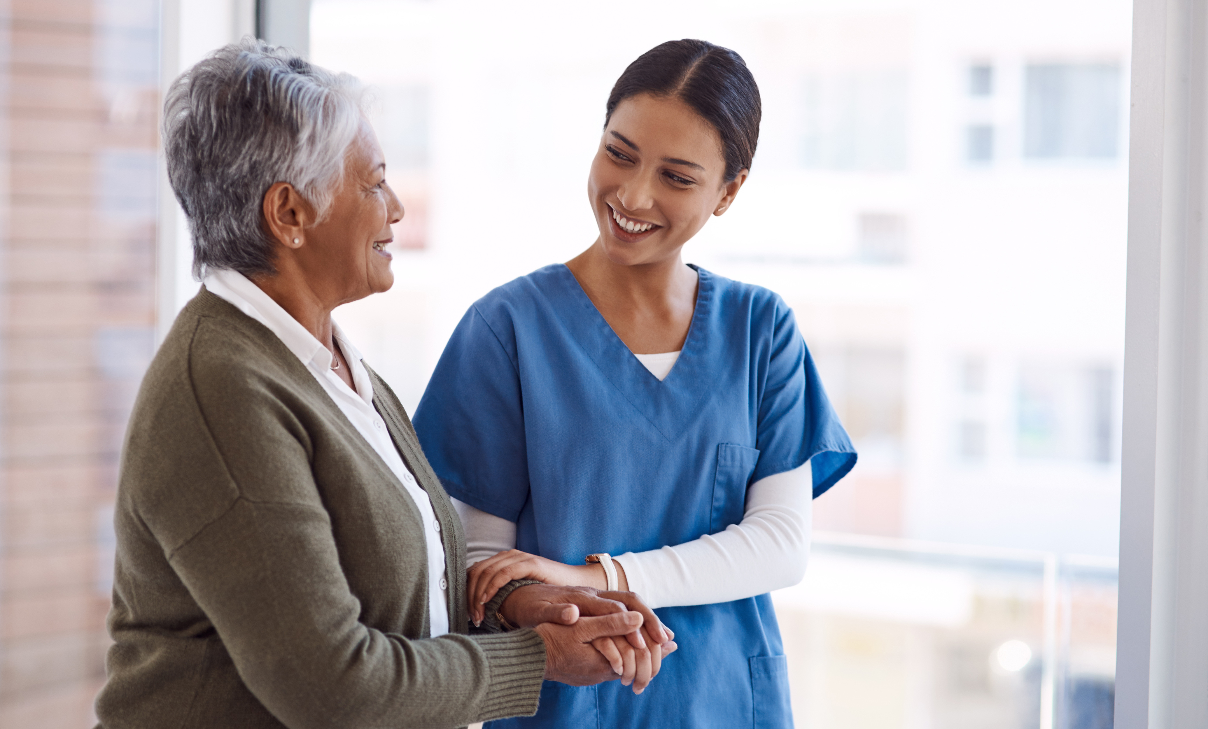 An Advinia Care nurse holding hands with a smiling senior resident