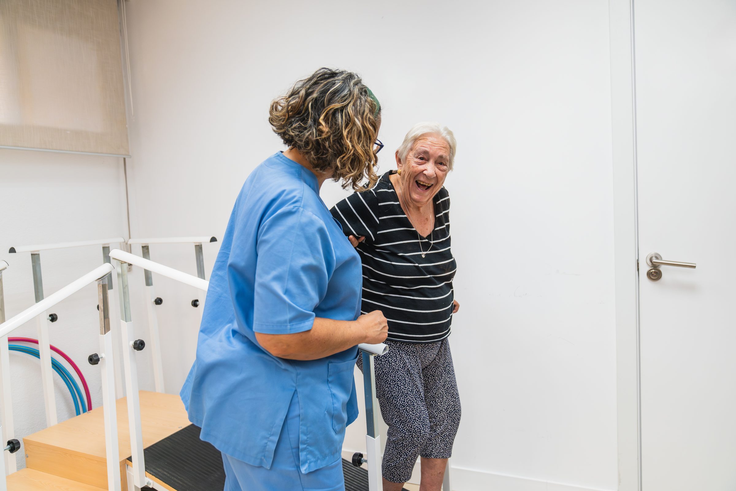 A caregiver helping a joyful resident during a rehabilitation session at an Advinia Care community